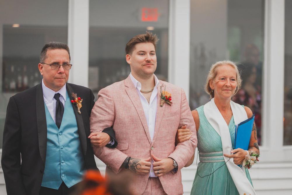 Wedding party members in formal attire featuring pink and blue color coordination stand together during ceremony.