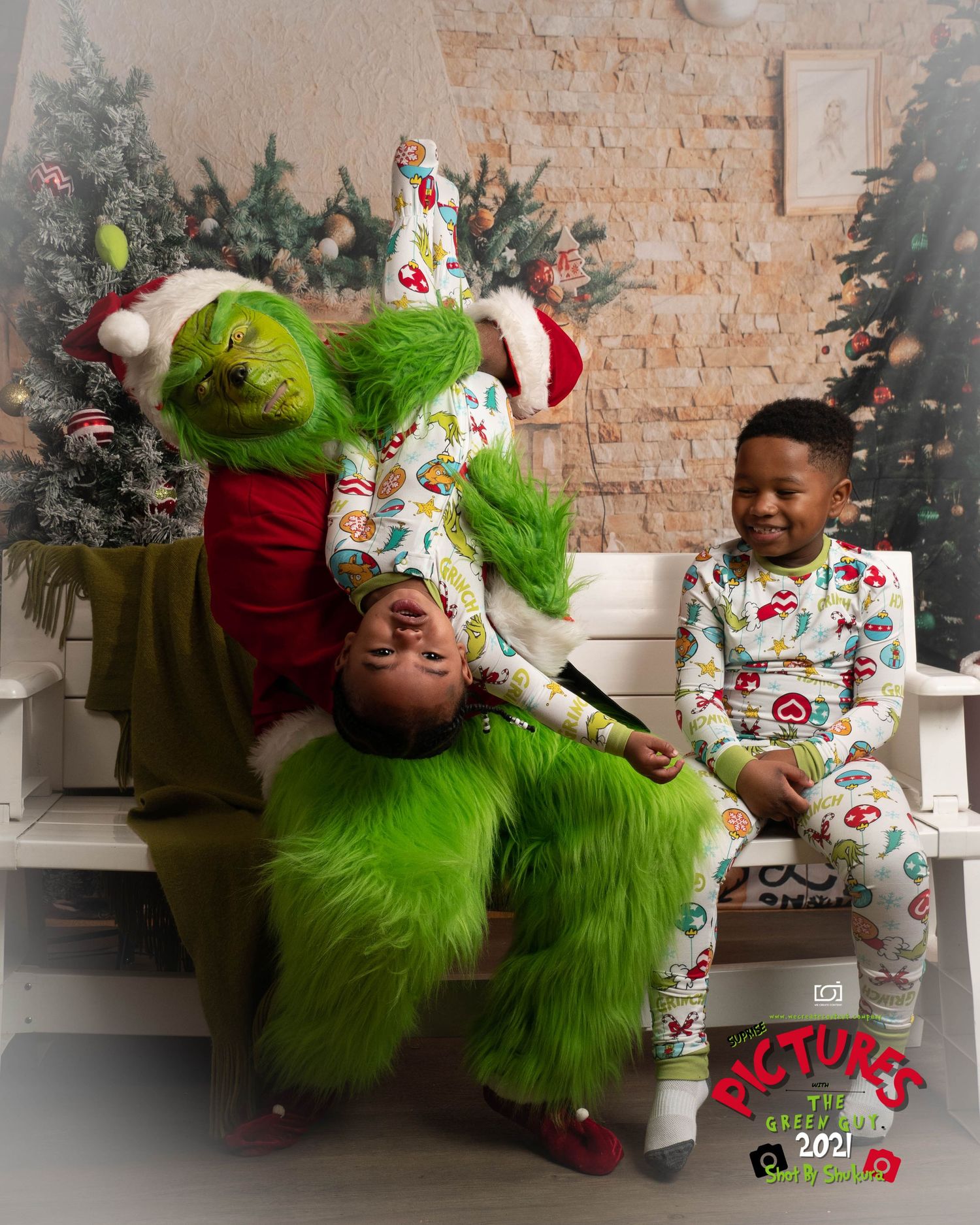Holiday scene with playful poses in festive pajamas next to decorated Christmas tree and brick wall backdrop.