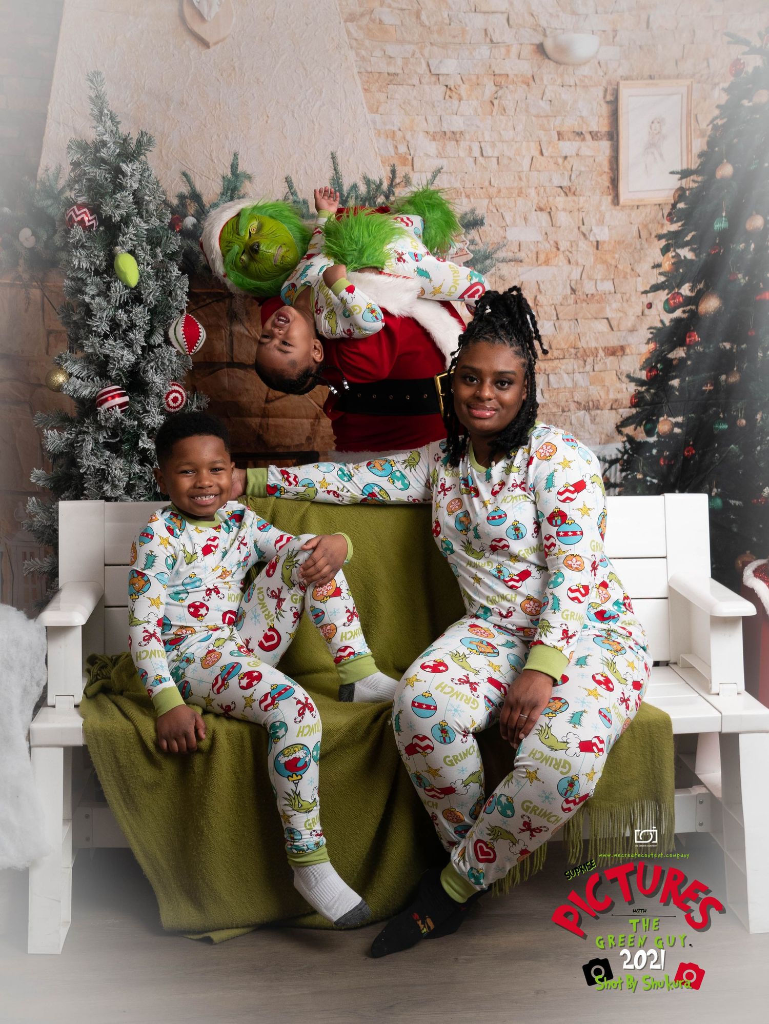 A festive holiday photo featuring people wearing matching Christmas pajama sets against a brick wall backdrop.
