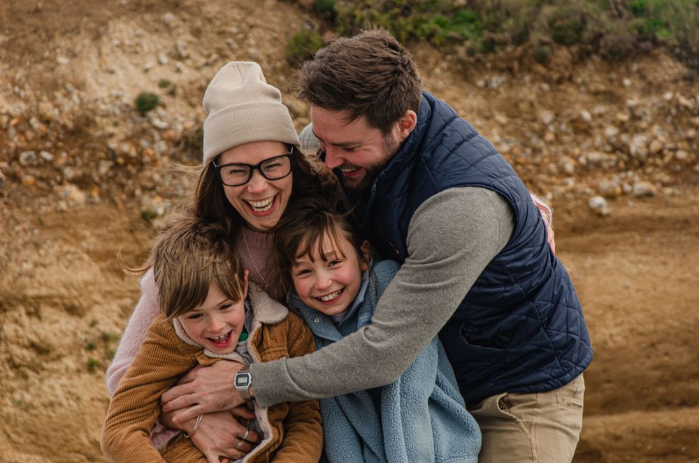 family of four hugging and laughing together