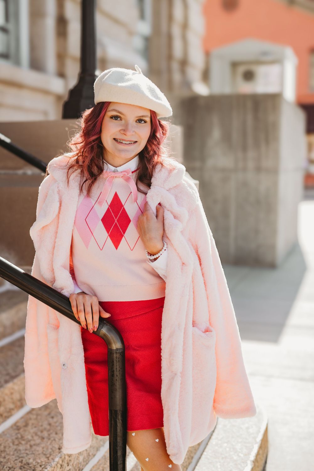Vintage-inspired fashion shoot featuring pink coat and red dress against classic architecture.