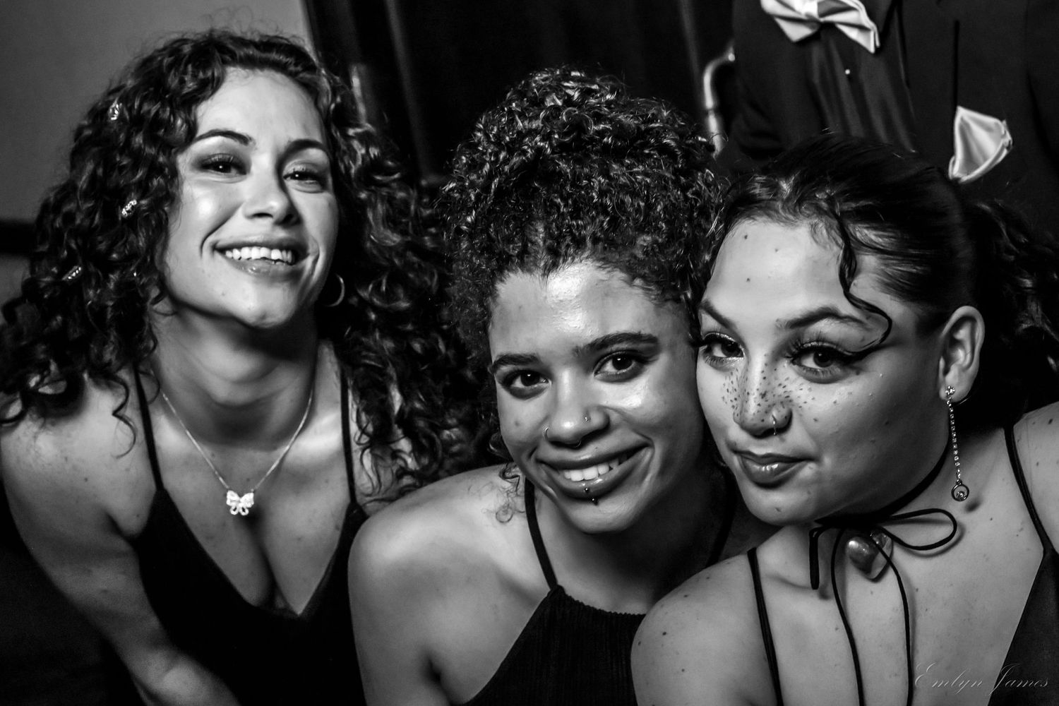Black and white close-up portrait of three friends smiling and laughing together.