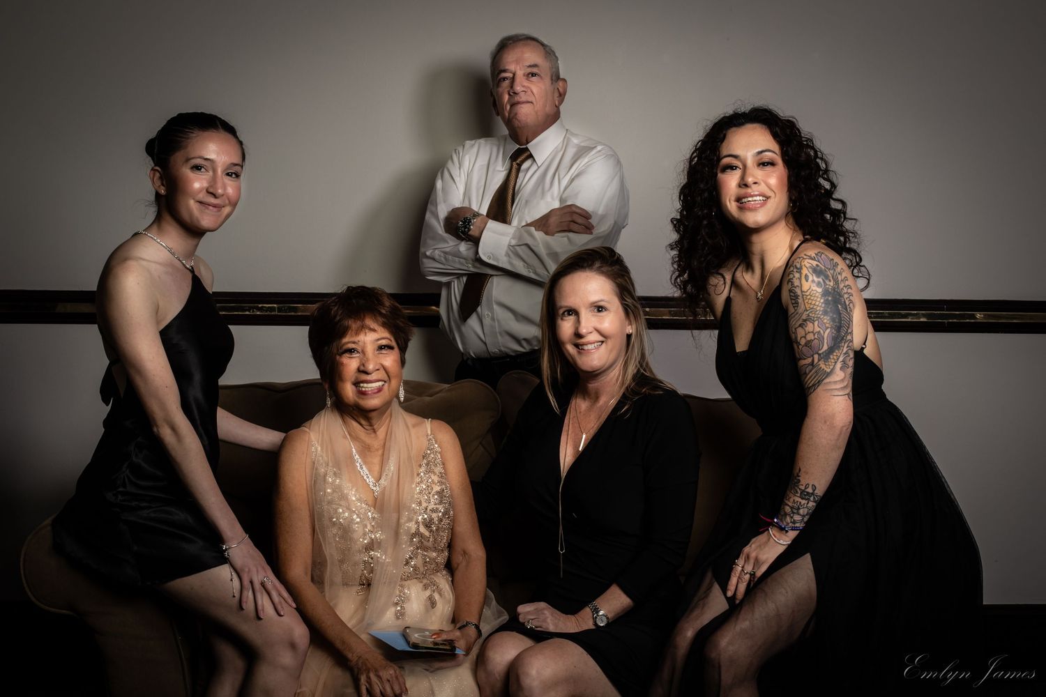 Studio portrait of a group in black attire against a minimalist background.