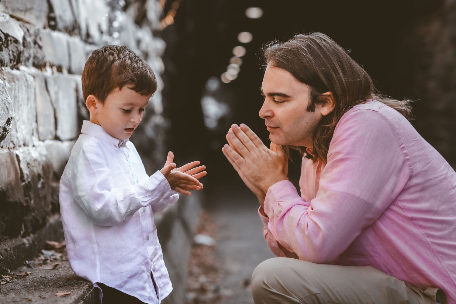 Parent and child playing together near a stone wall.