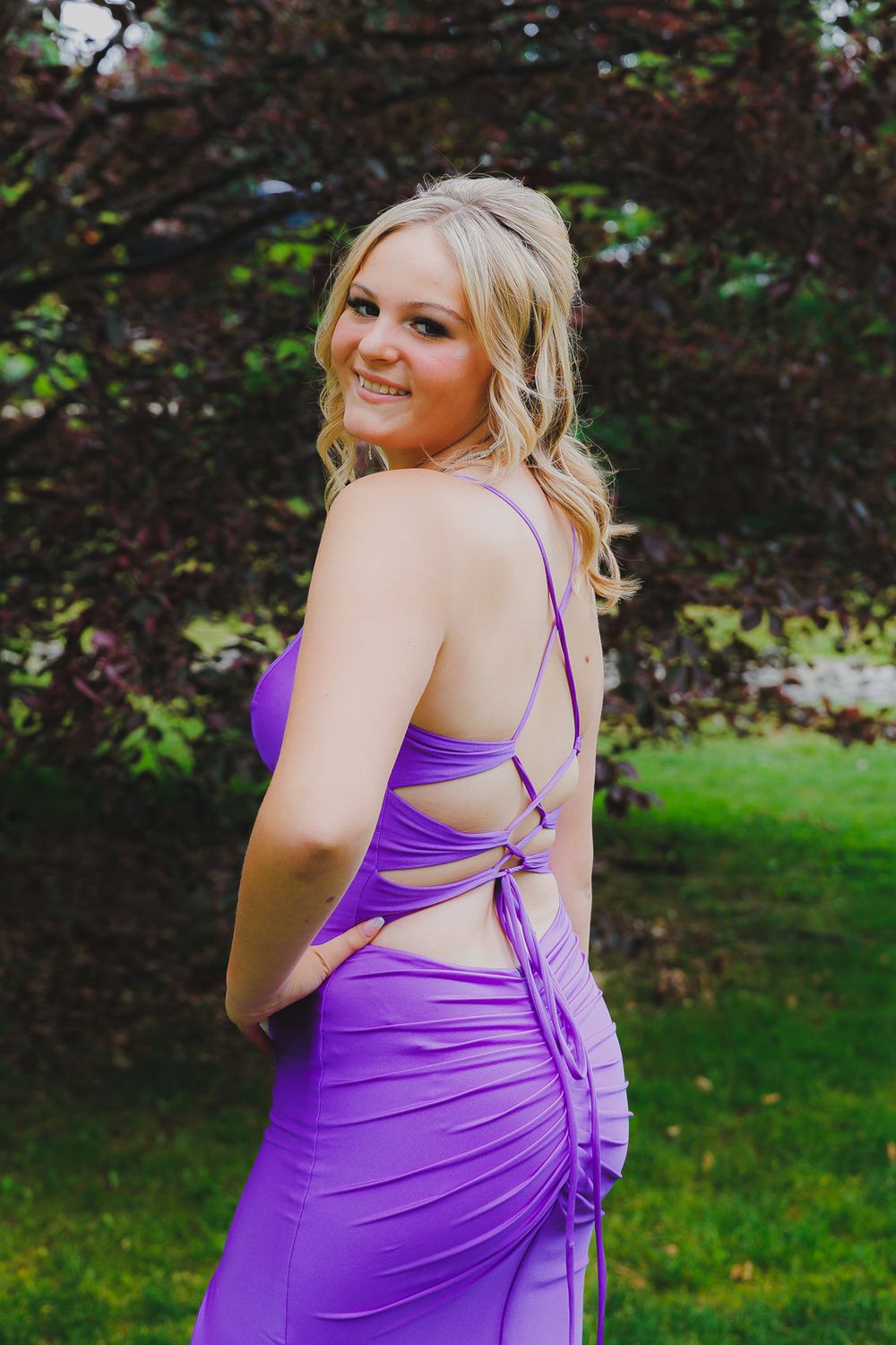 Purple formal dress with laced-up back detail photographed in garden setting.