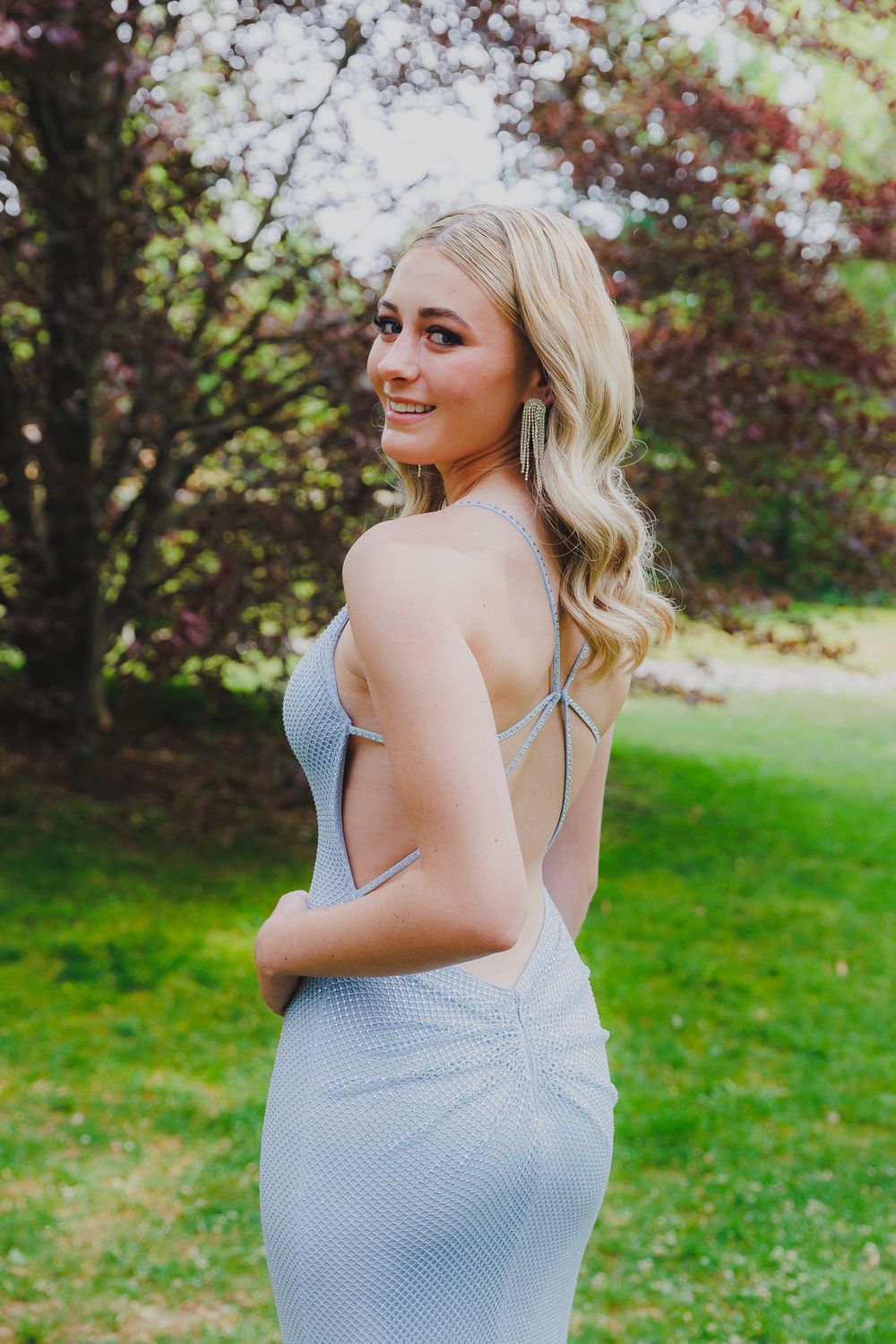 Elegant silver form-fitting dress photographed against natural outdoor backdrop.