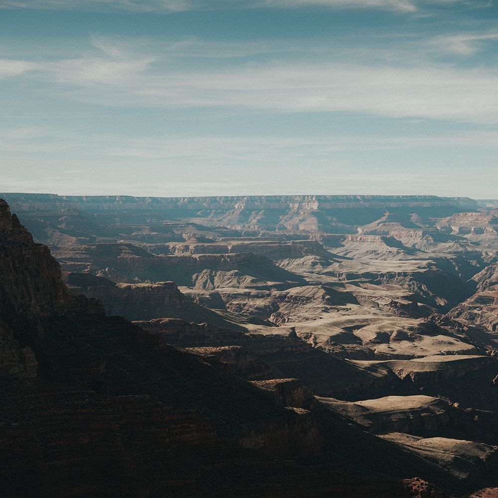 Sweeping vista of Grand Canyon's layered cliffs and valleys under blue sky.