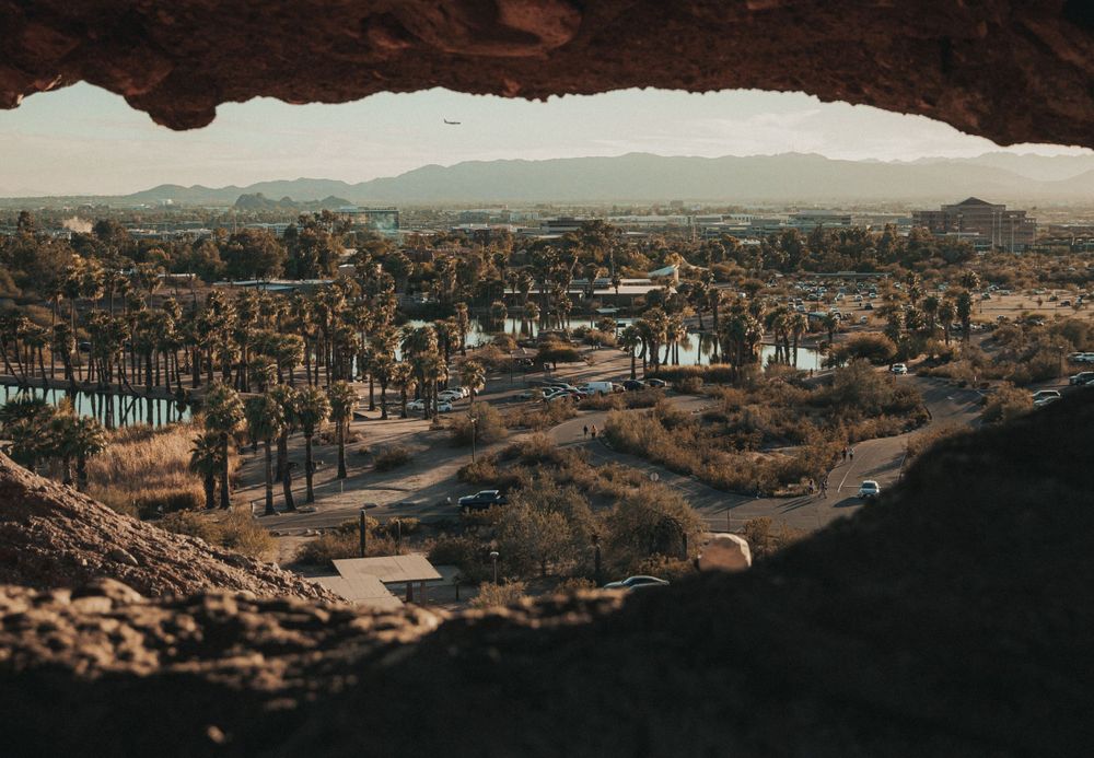 Aerial view of a desert town with houses and streets visible through a cave opening.