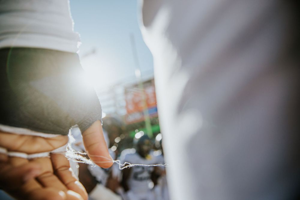 Close-up detail of two hands passing something between them in bright sunlight.