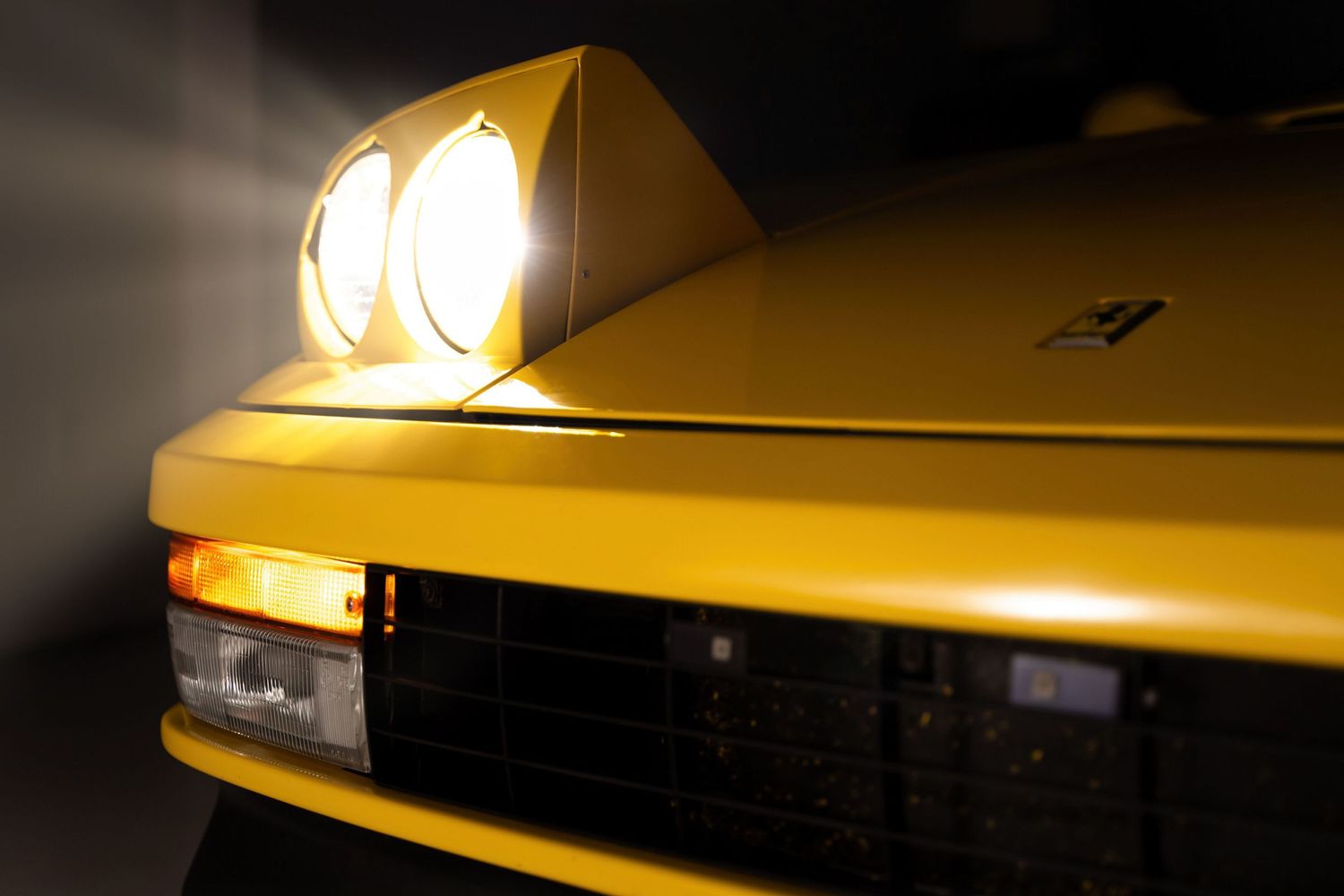 Yellow sports car headlights glowing dramatically in the dark.