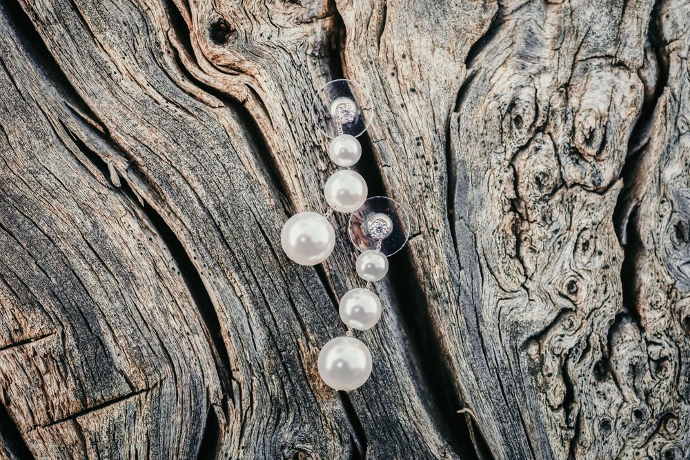 Pearl and crystal wedding jewelry arranged on textured wooden surface.