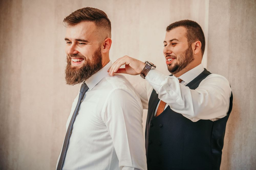 Groomsman helping adjust another groomsman's collar before the ceremony.