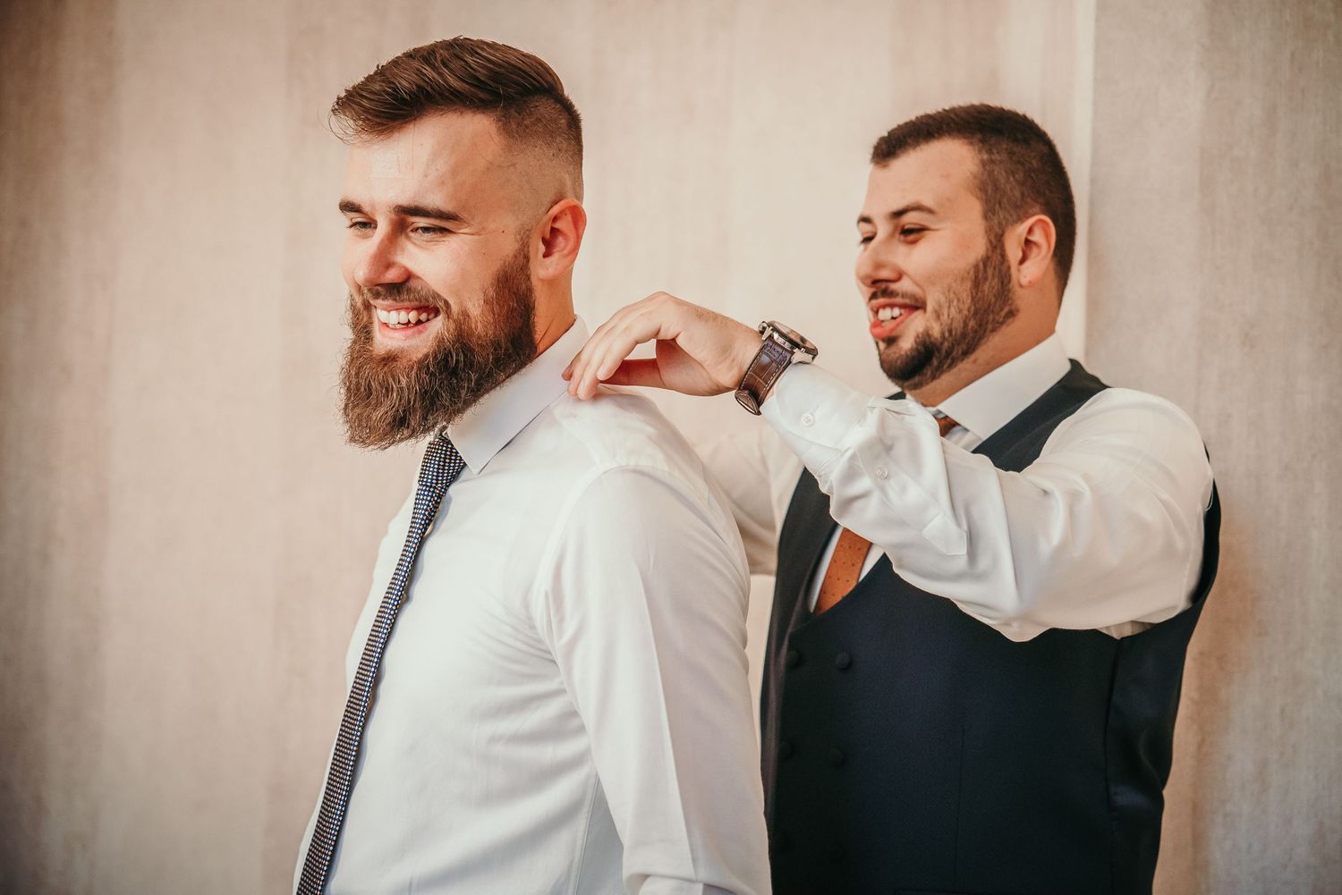 Groomsman helping adjust another groomsman's collar before the ceremony.