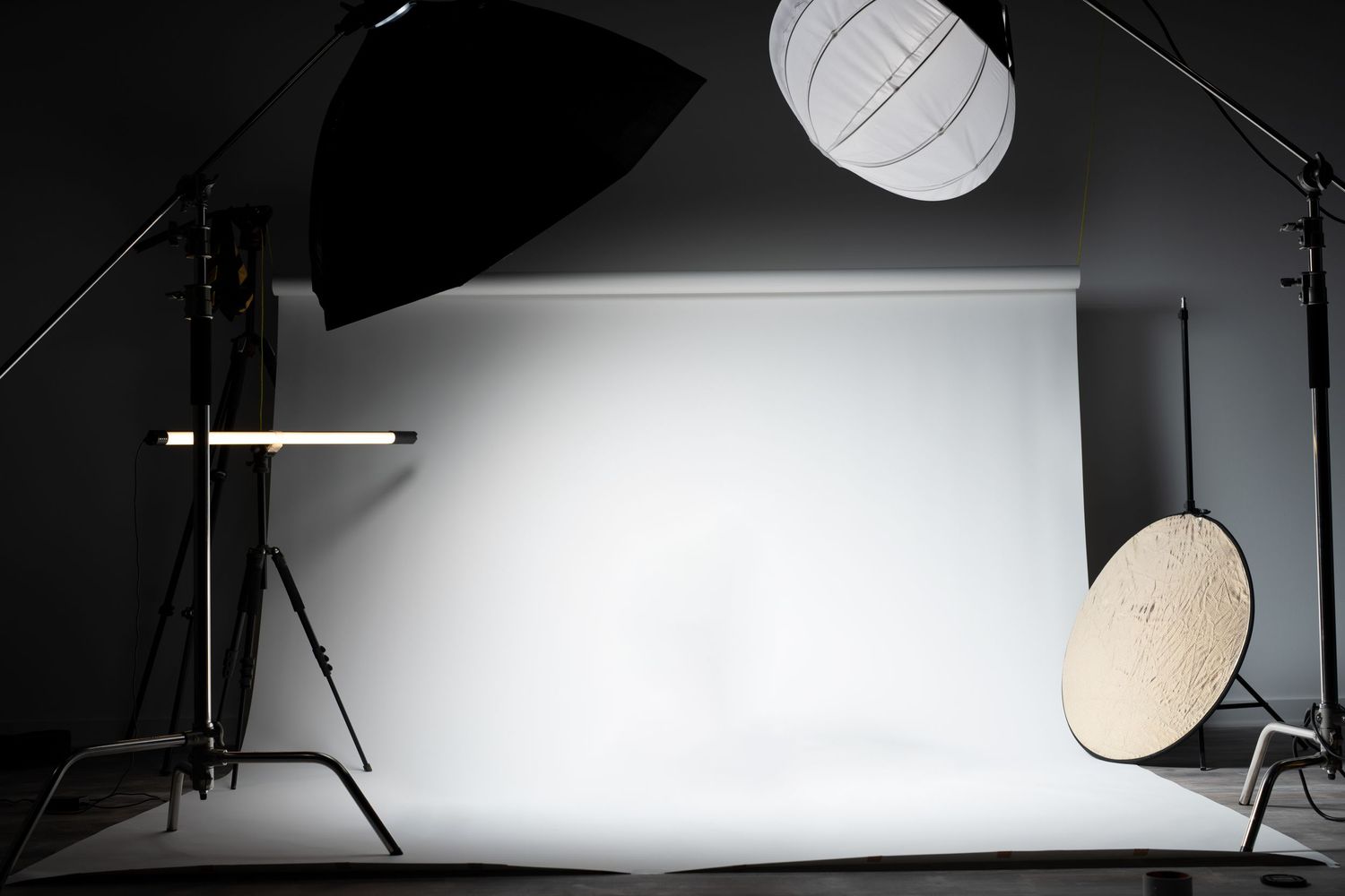 Professional photography setup with white backdrop, softboxes, and reflectors in studio.