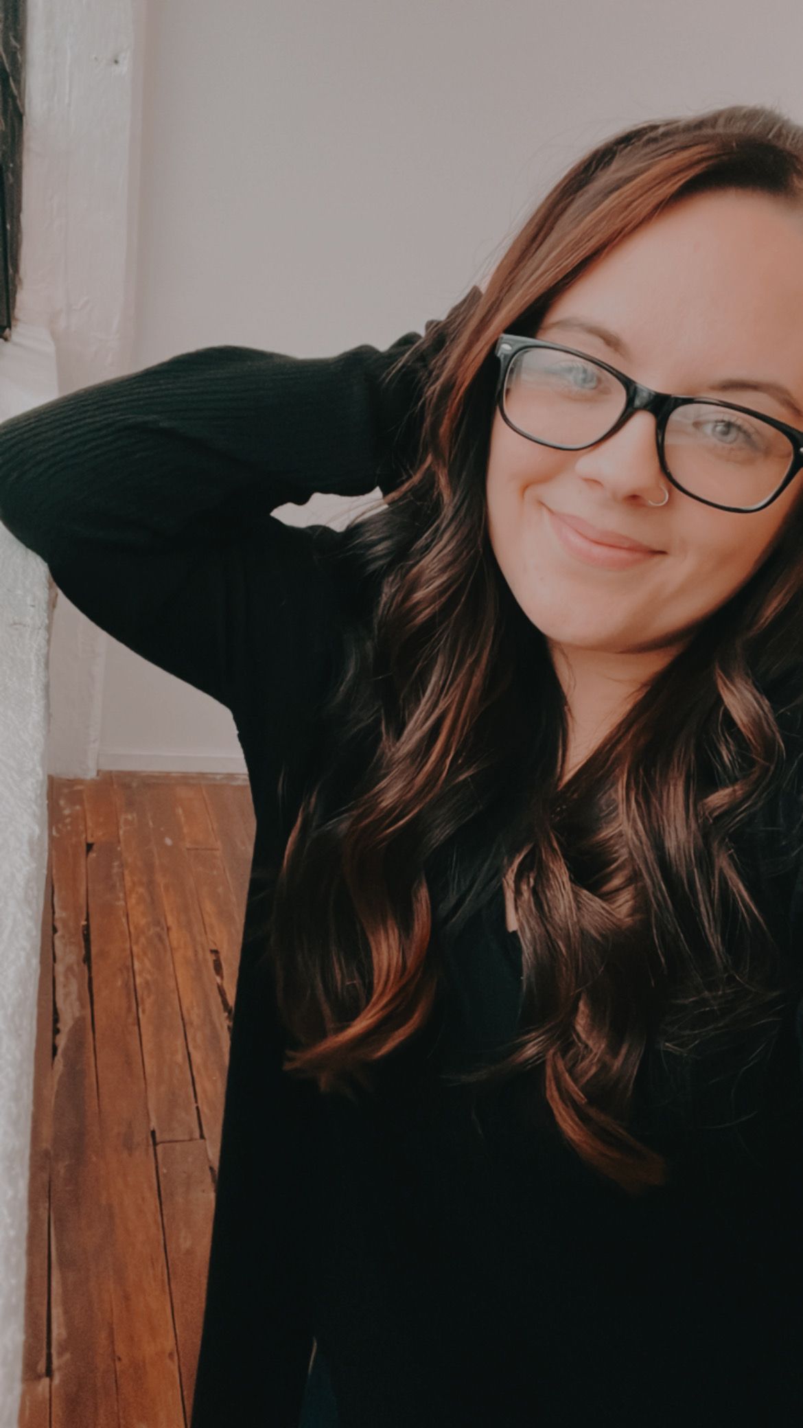 Person in black sweater takes selfie while smiling warmly at camera.