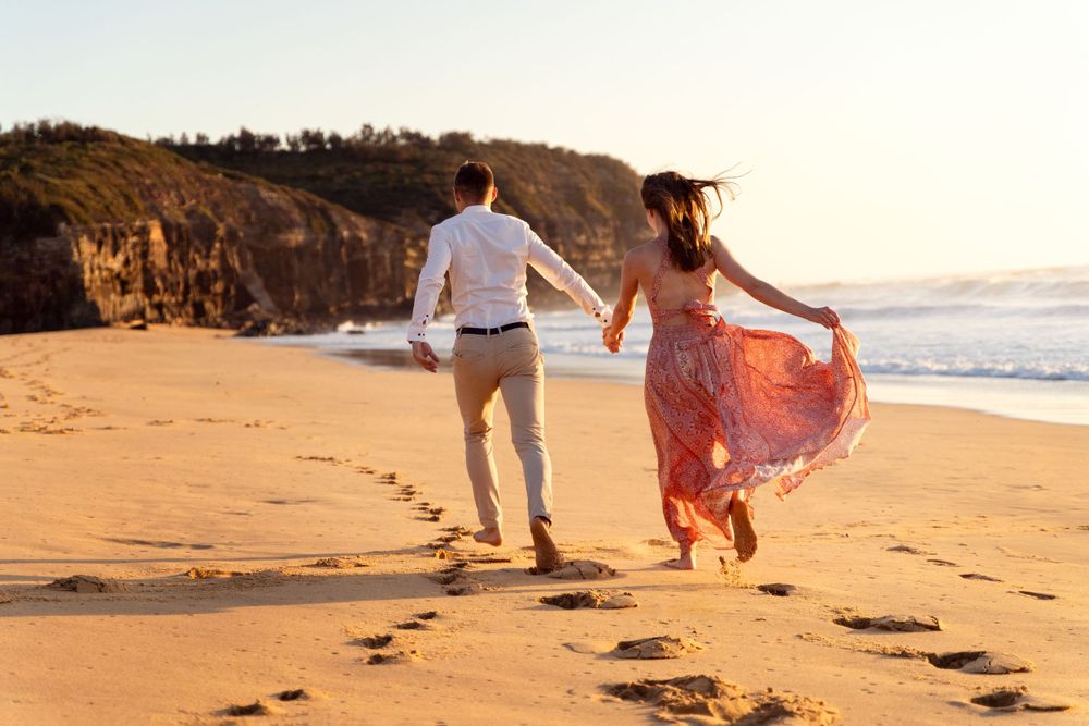couple running away during an engagement photoshoot at Turimetta beach