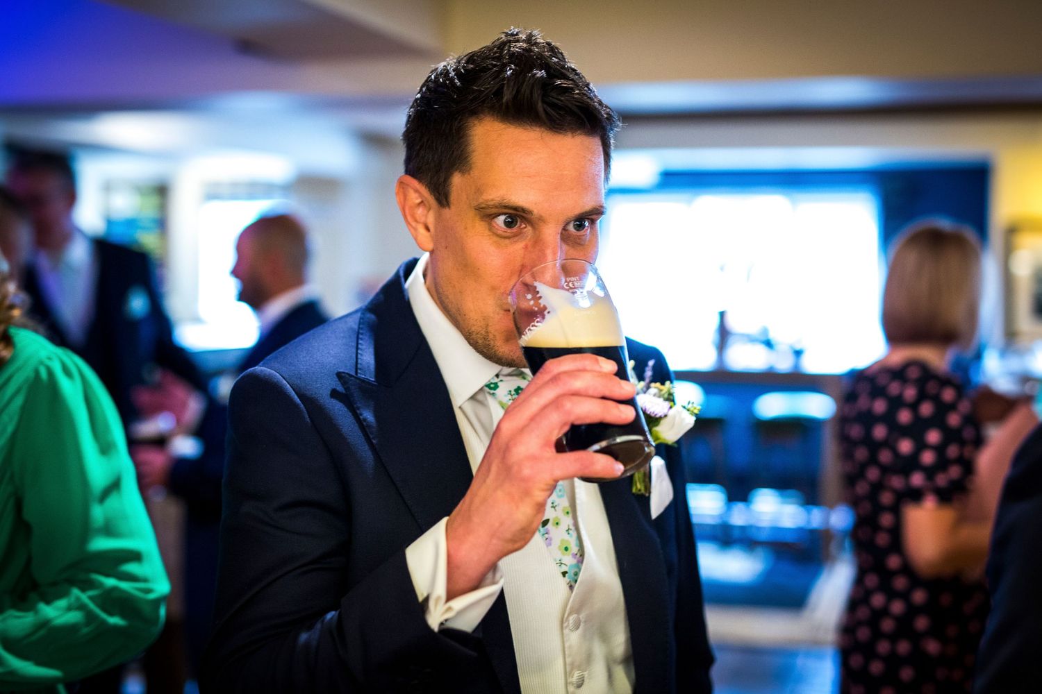 Man in formal attire sips drink at evening event.