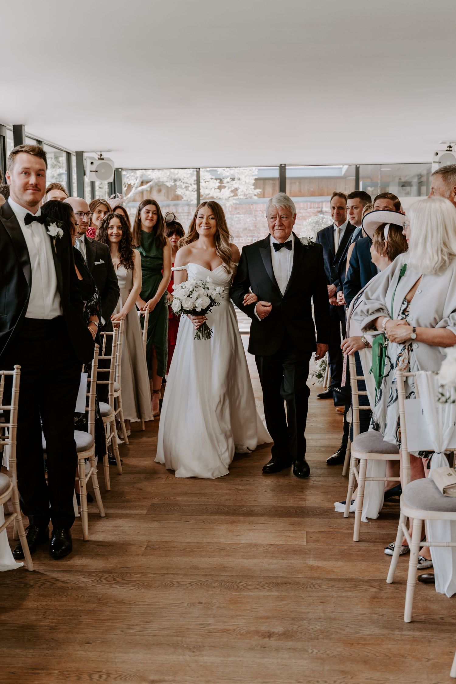 Bride walking down the aisle linked arms with her father.