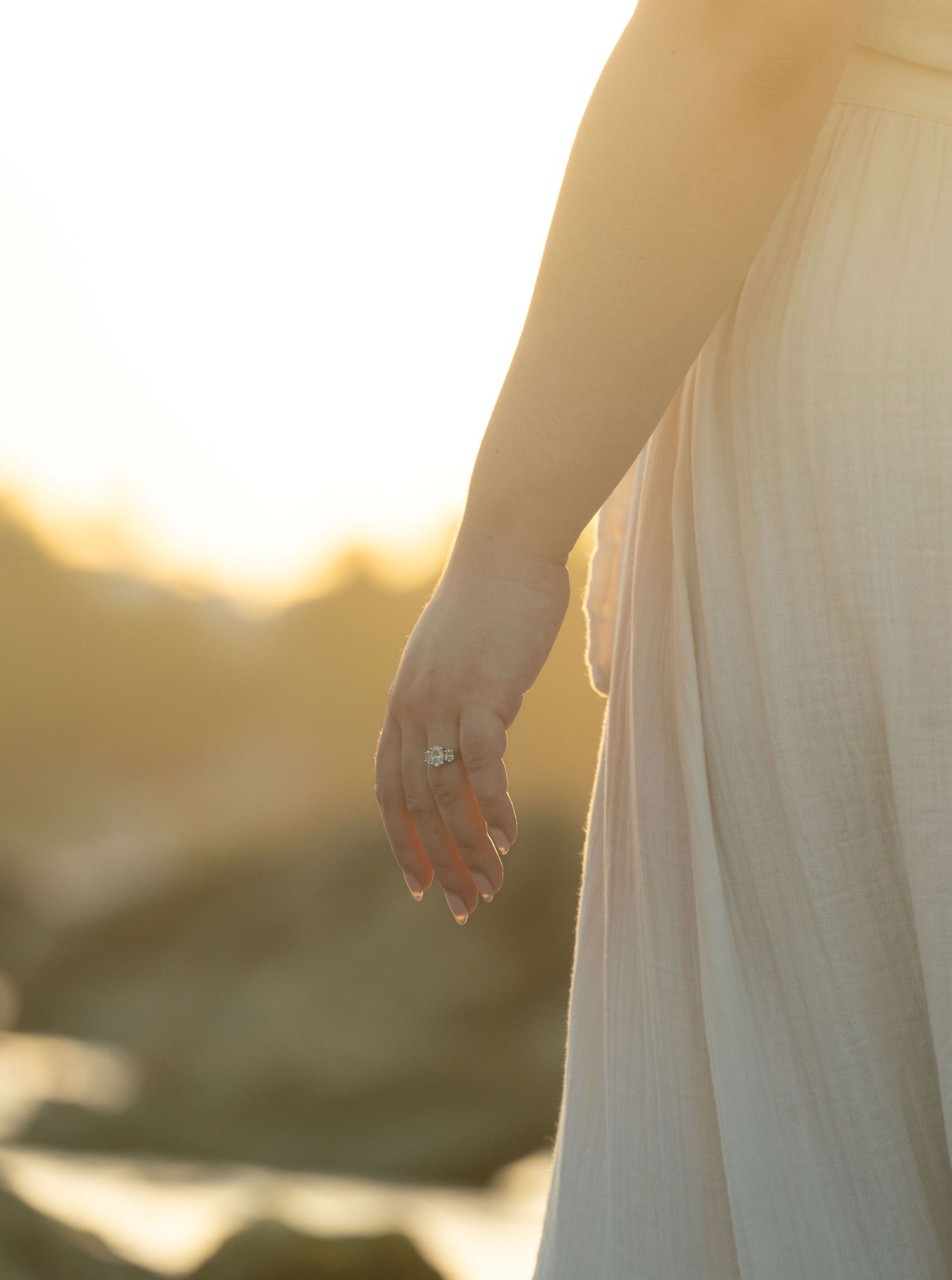 Ethereal sunlit close-up of flowing white dress fabric during golden hour.