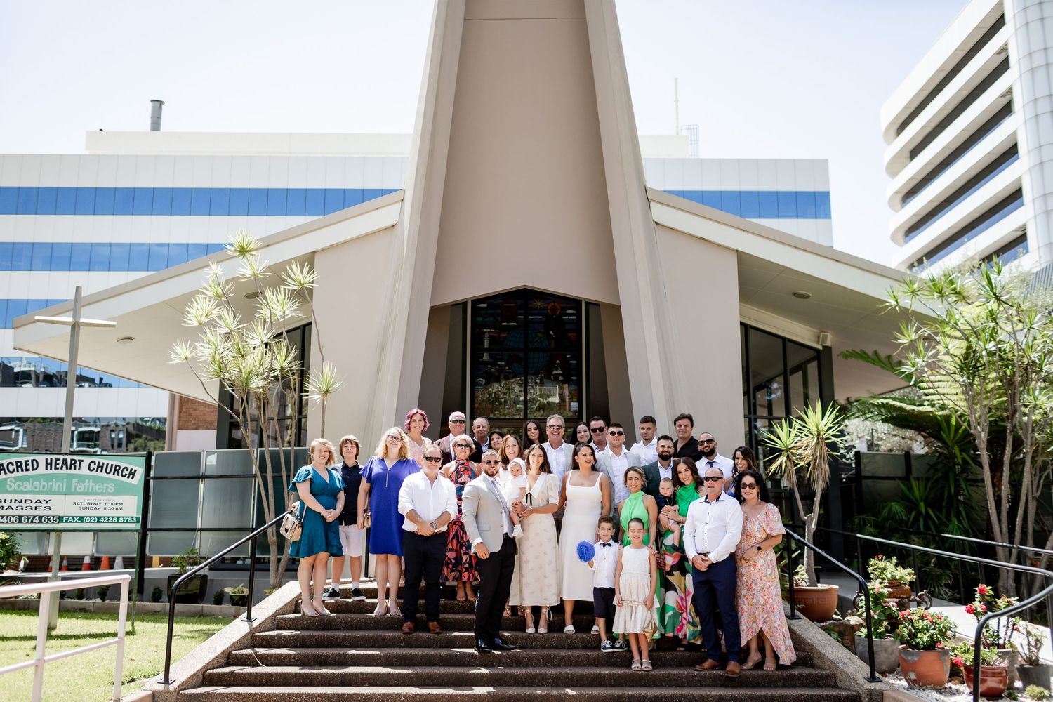 Modern church exterior with contemporary architecture and gathering of guests on front steps.