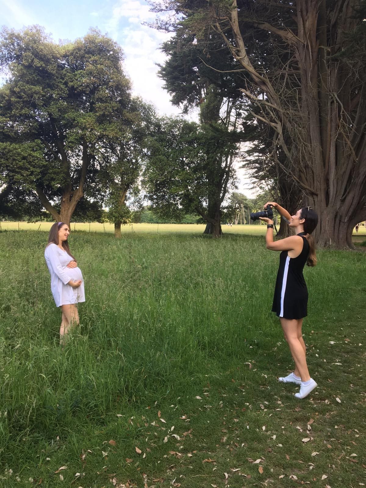 A behind-the-scenes shot of a photographer capturing maternity photos outdoors.