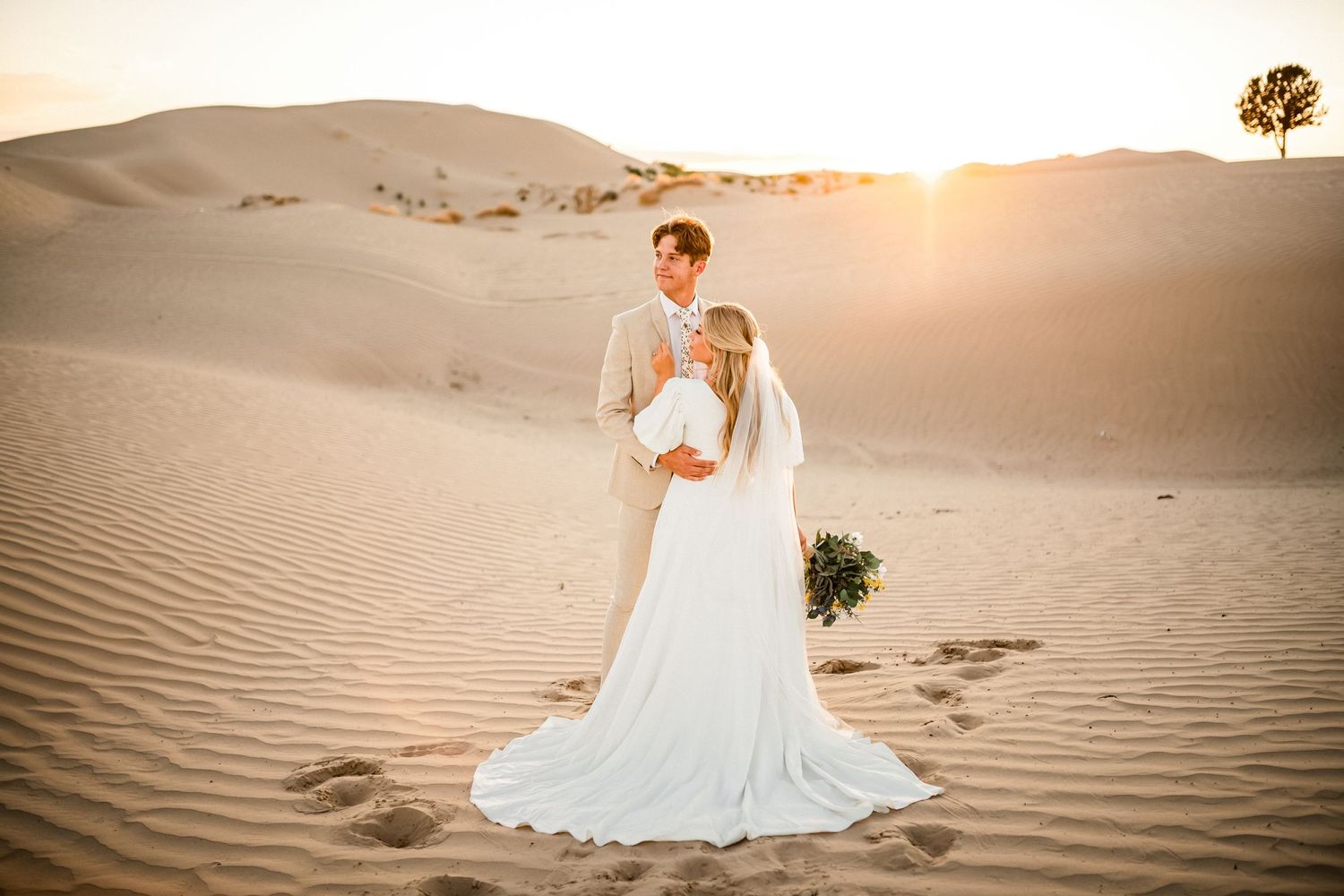 Bridal portraits in white dress among desert sand dunes at golden hour.