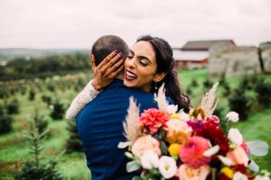 A romantic moment captured with a vibrant bouquet of pink and red flowers in the foreground.