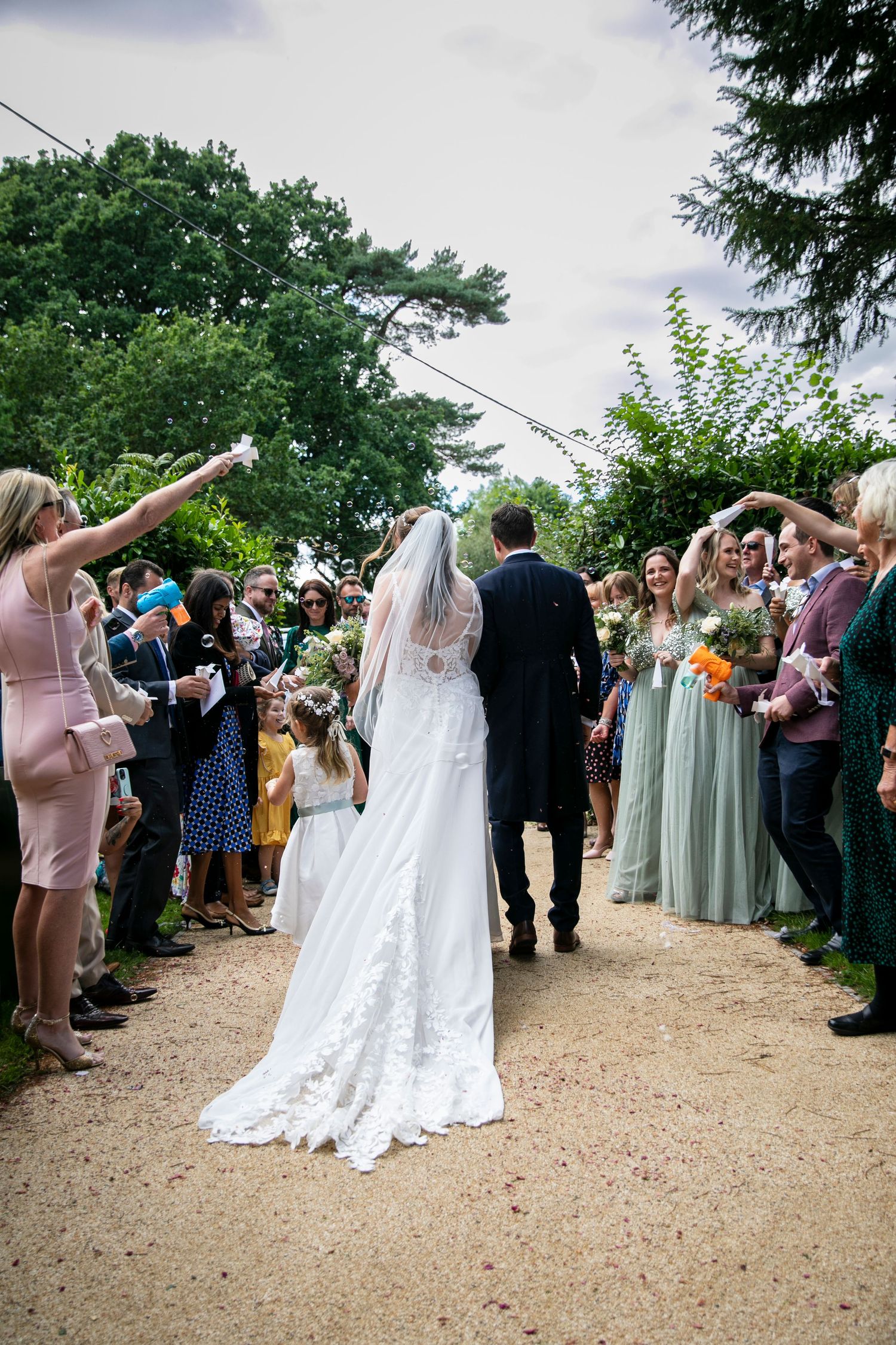 Wedding guests form receiving line outdoors for newlyweds.