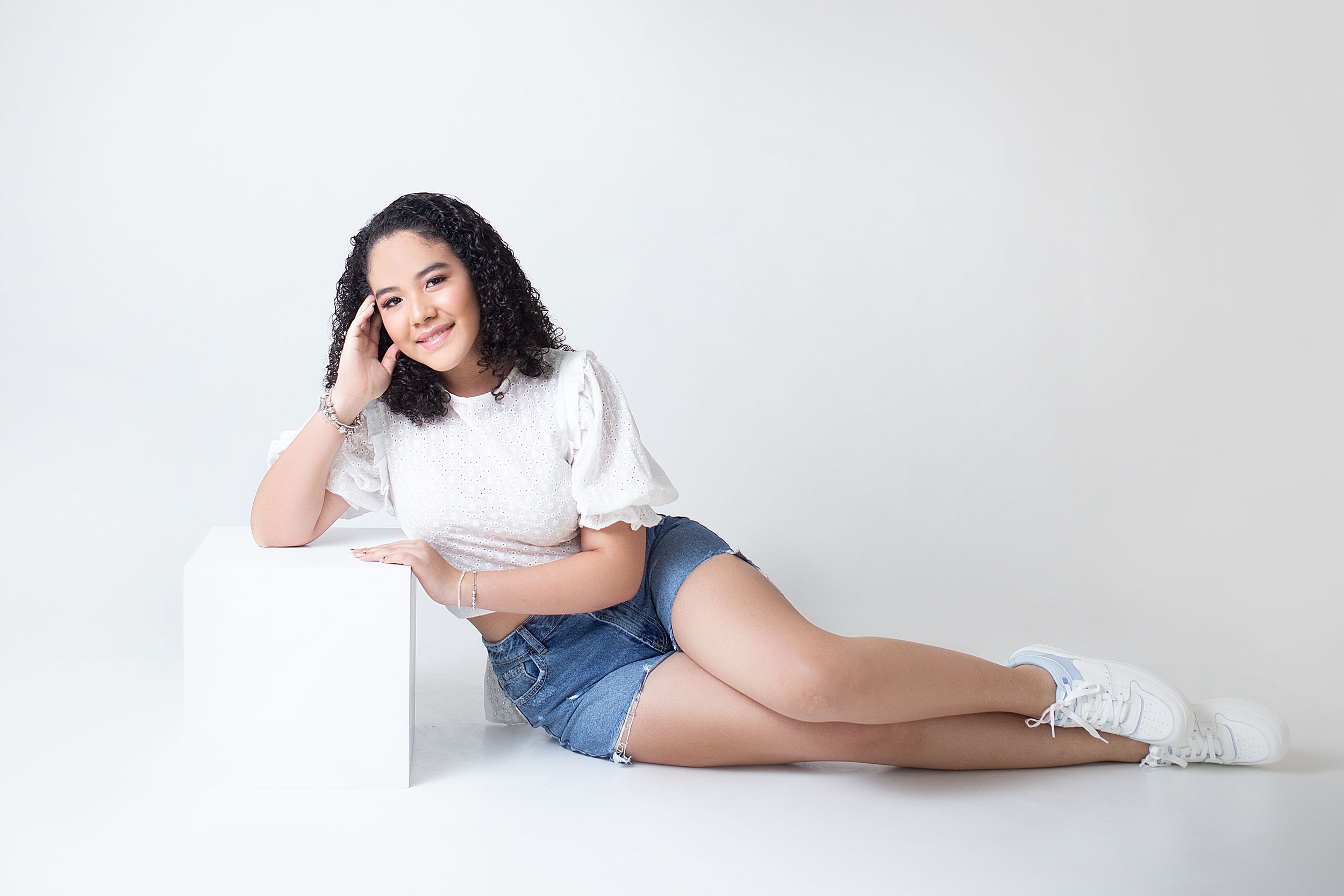 Casual portrait series showing person in white shirt and denim relaxing on white background.