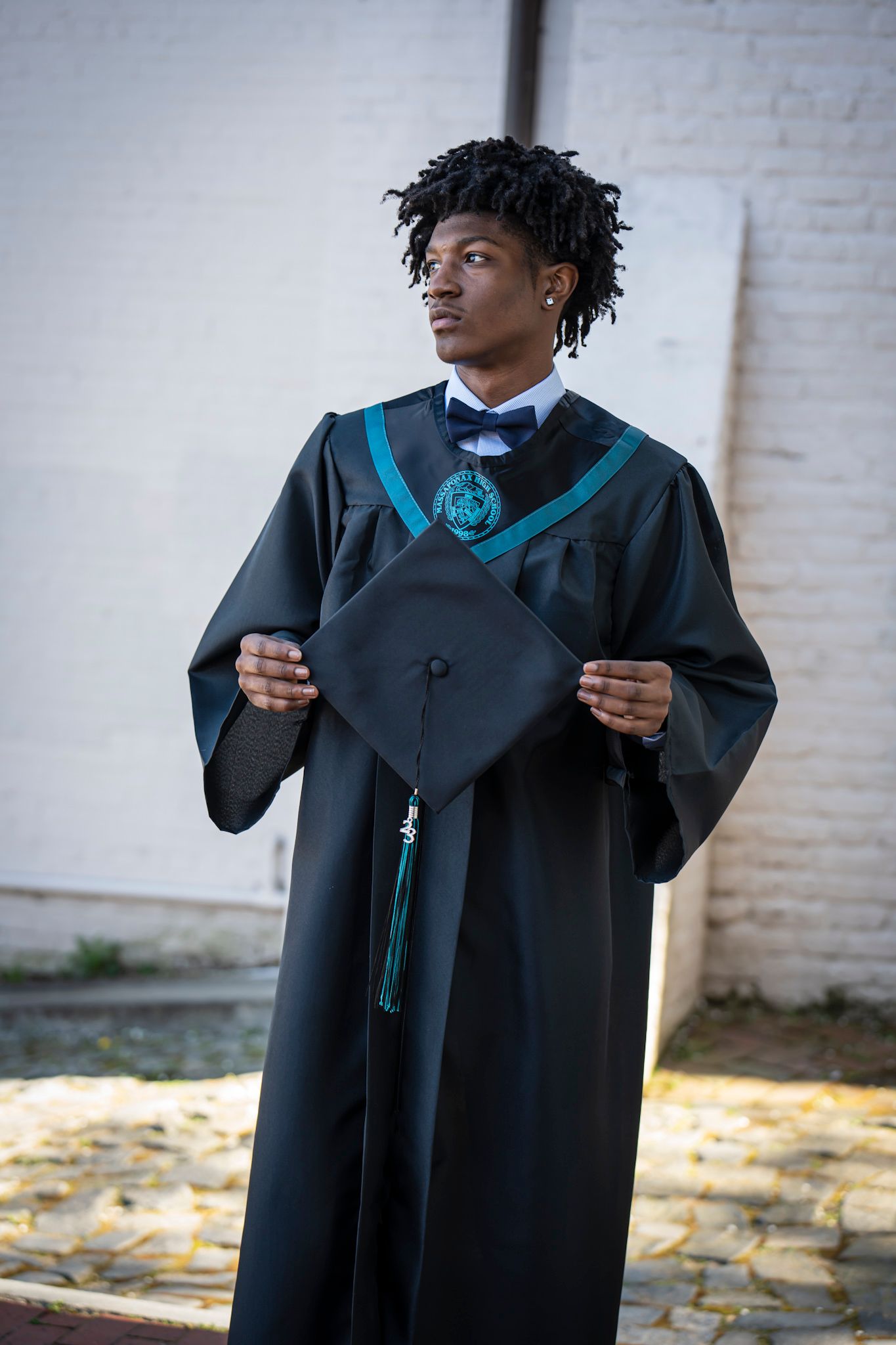 A graduation portrait showing academic regalia with blue accents and mortarboard cap.