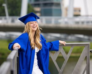 High school senior laughing out loud with her cap and gown in holland mi