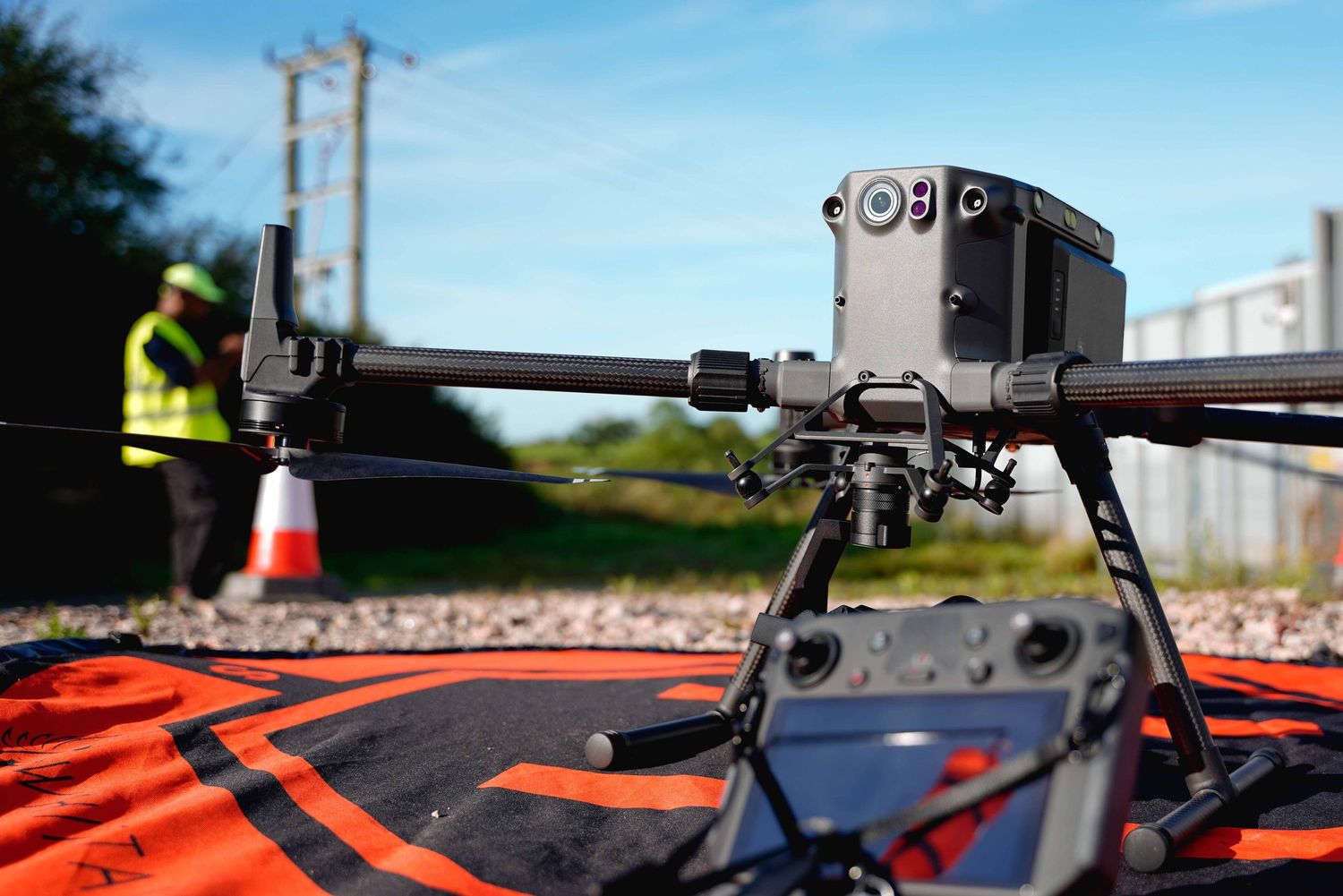 Close-up of a professional drone camera mounted on equipment with orange safety markers visible.