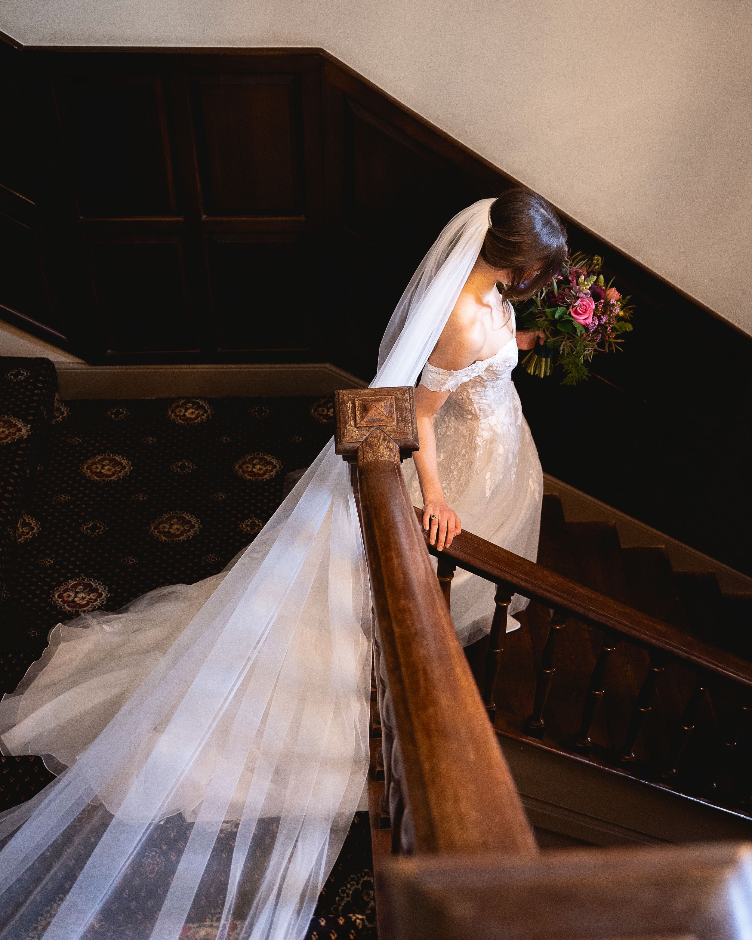 Artistic shots of a bride's flowing white dress and veil descending wooden stairs.