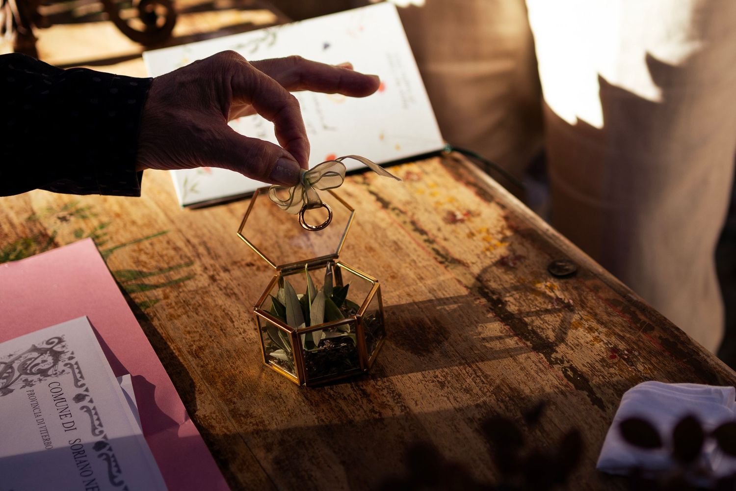 Hand placing a decorative element on a rustic wooden surface with papers nearby.