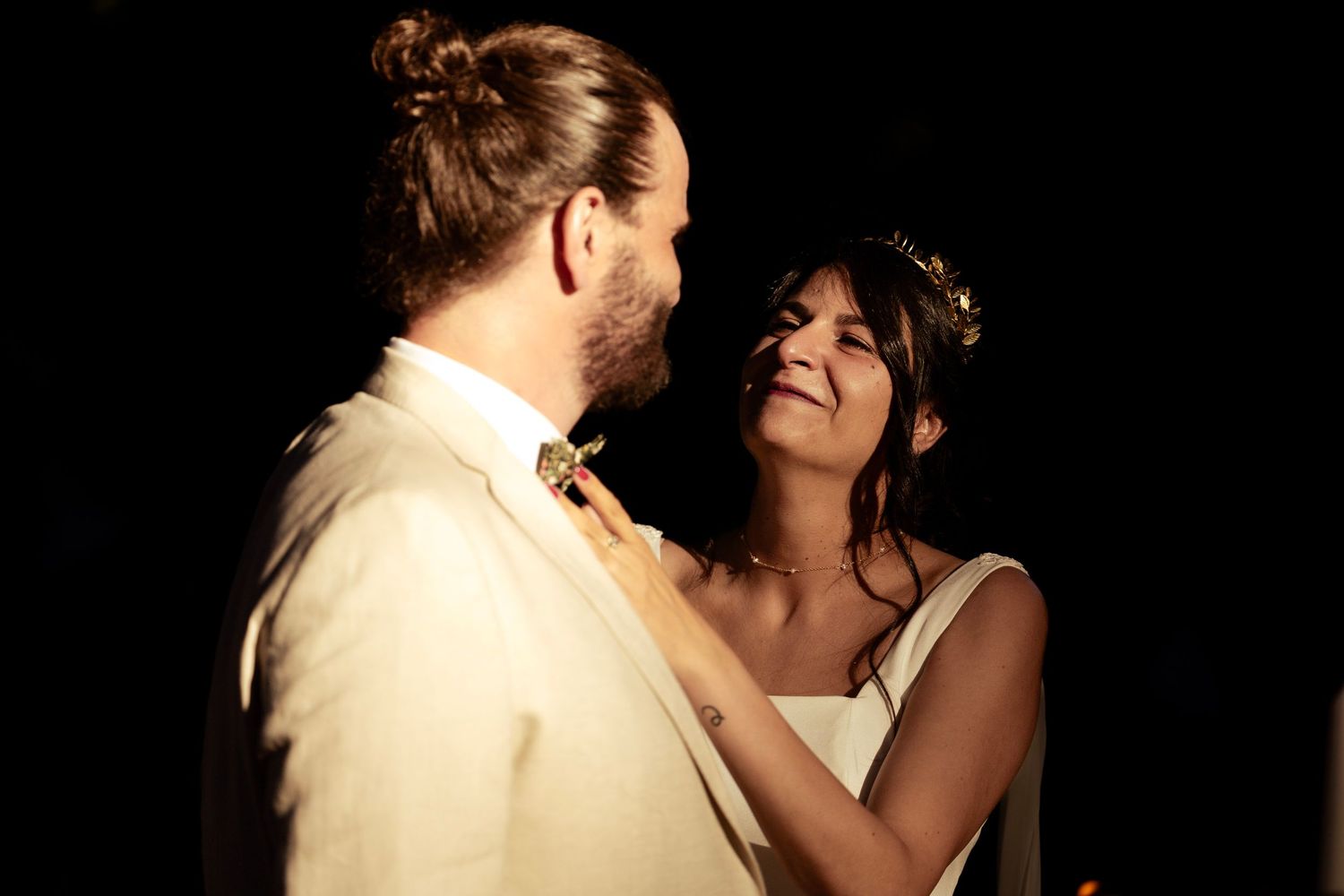 Intimate moment between newlyweds during their wedding reception against dark background.