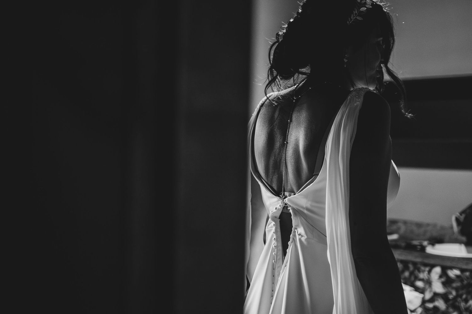 Back view of an elegant white dress with an open back and tied bow detail in black and white.