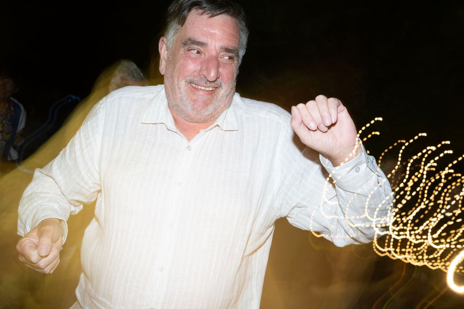 Dancing enthusiast enjoys a lively moment at a party with blurred light trails in the background.