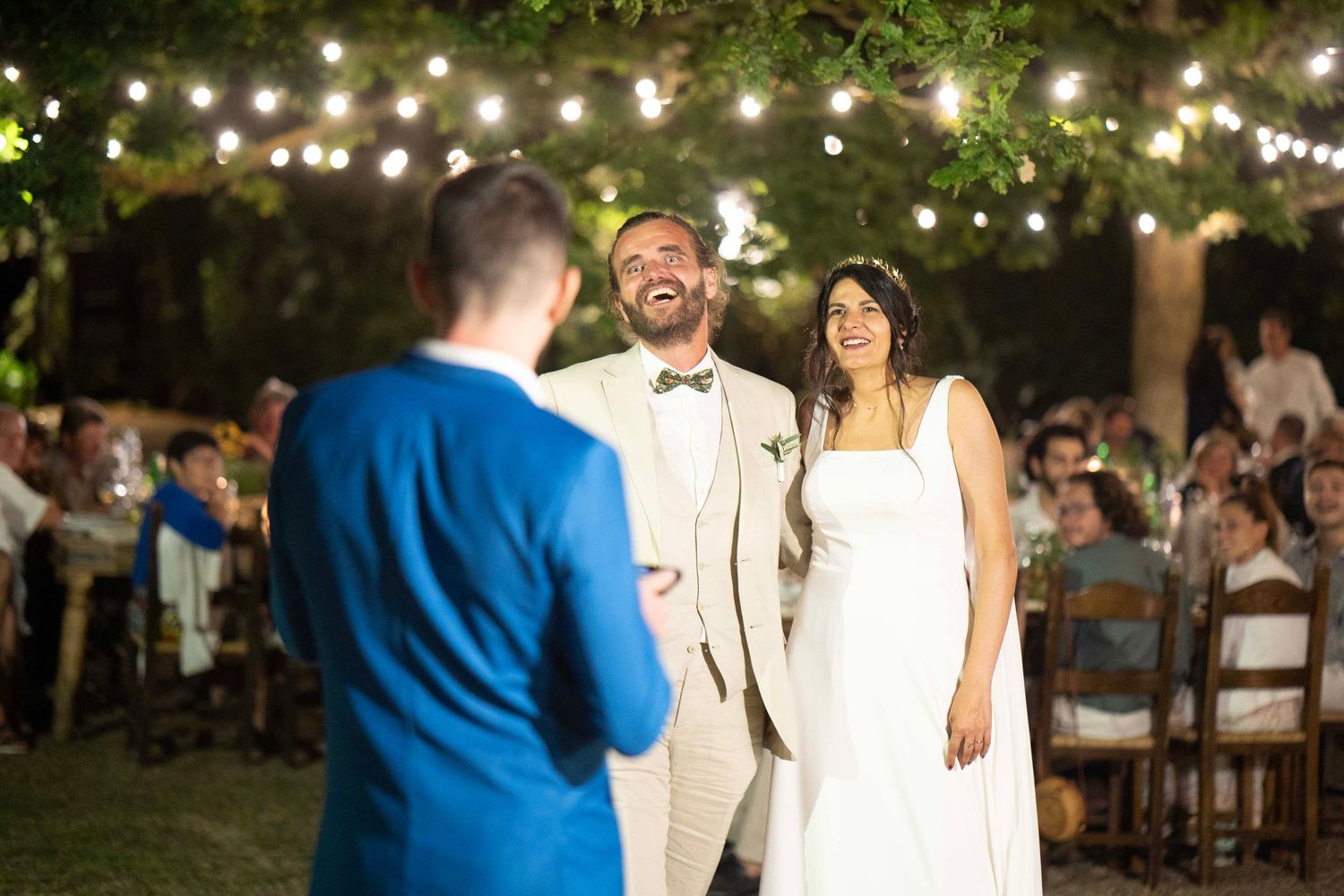 Evening outdoor wedding celebration with string lights and guests.