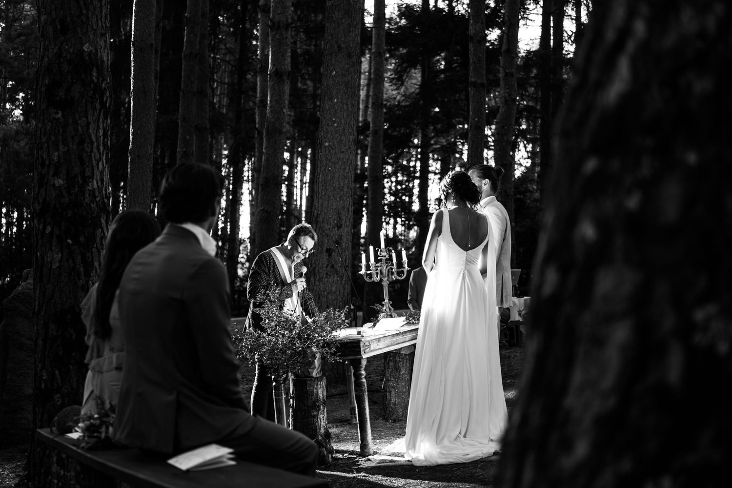 Black and white photo of a wedding ceremony in a serene forest setting.