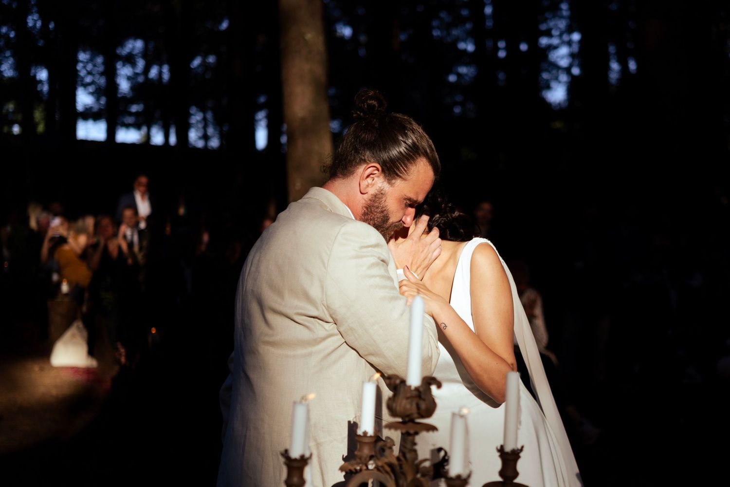 A tender moment between newlyweds during their forest wedding with candlelight.