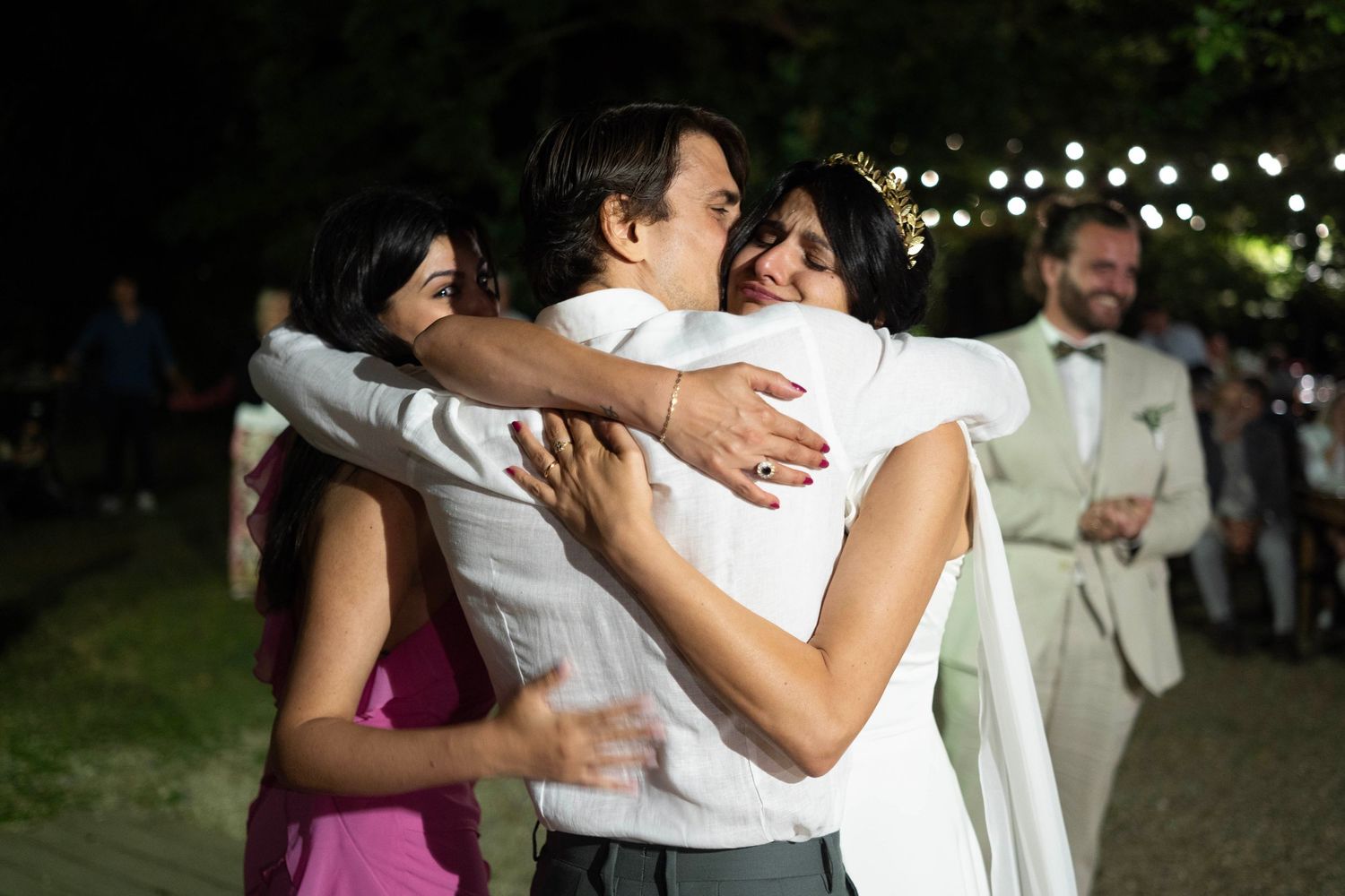 Emotional group hug during wedding celebration.