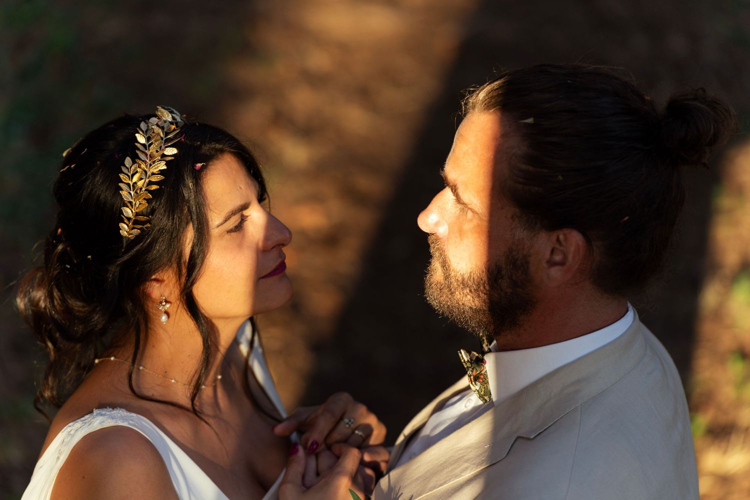 A romantic sunset portrait of a couple in wedding attire sharing a tender moment in golden light.