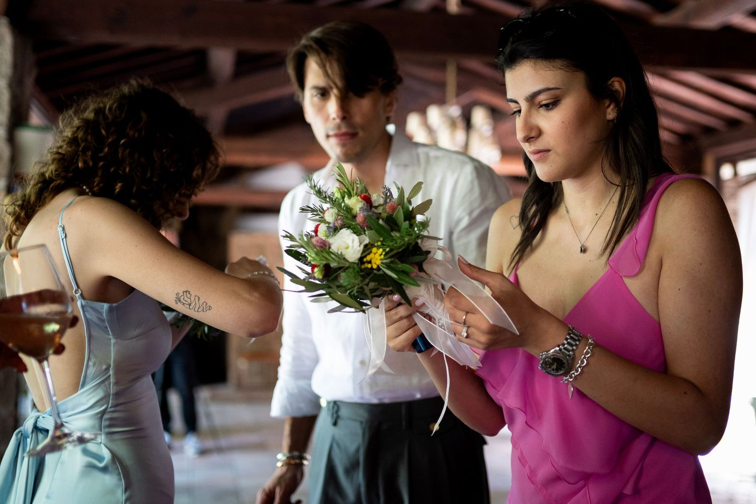Women in colorful dresses looking at a small bouquet during a celebration.