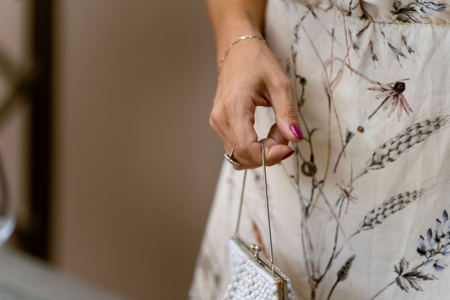 Close-up of hands holding a small tag attached to a floral patterned dress.