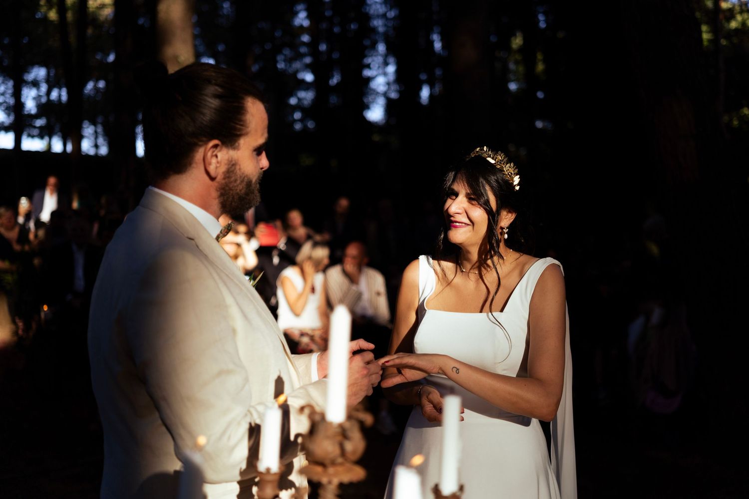 A couple exchanges vows during an intimate forest wedding ceremony at dusk.