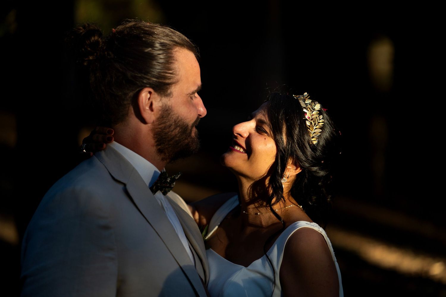 An intimate wedding portrait with dramatic lighting in a forest setting.
