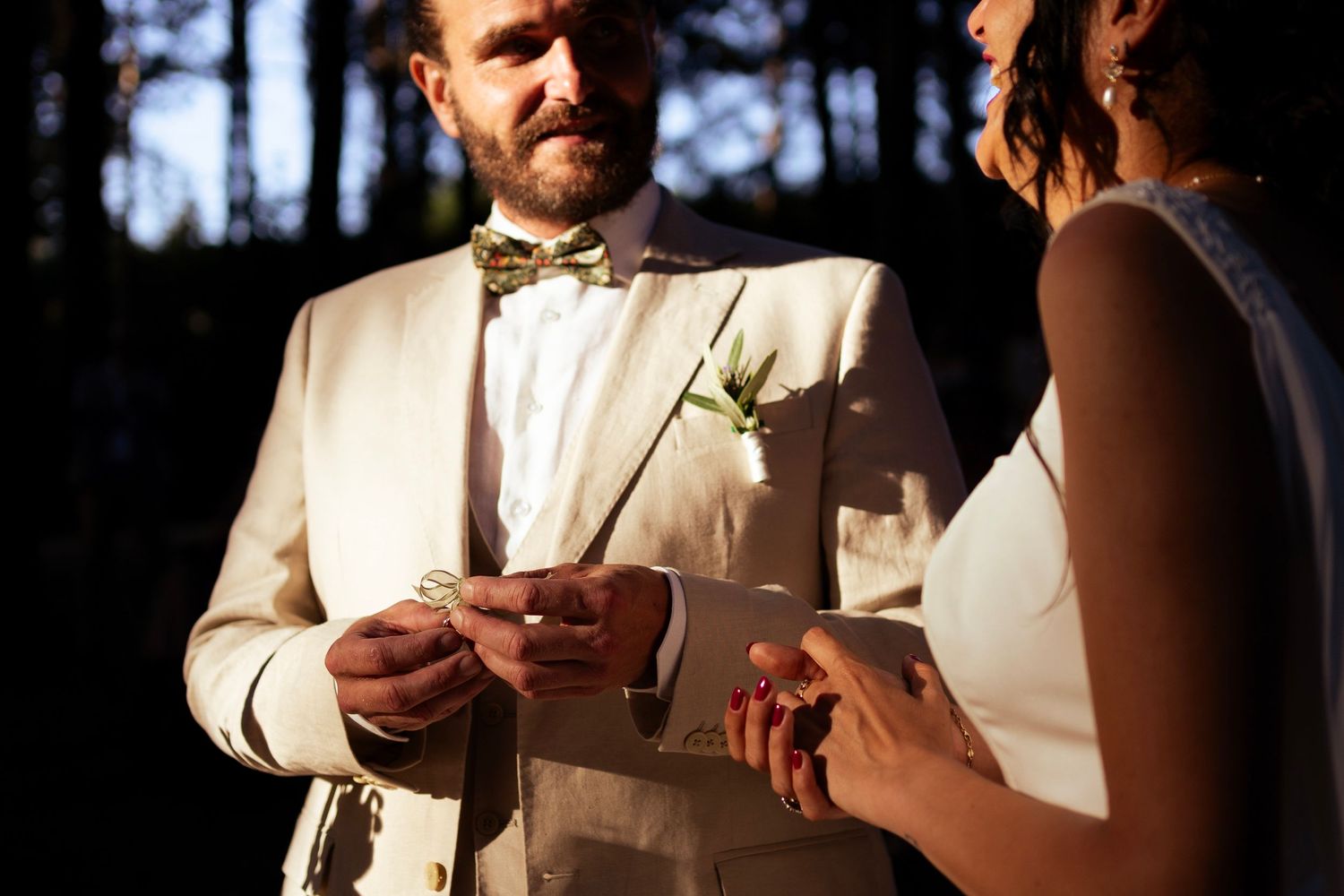 Couple exchanging vows or rings during an outdoor forest wedding ceremony.