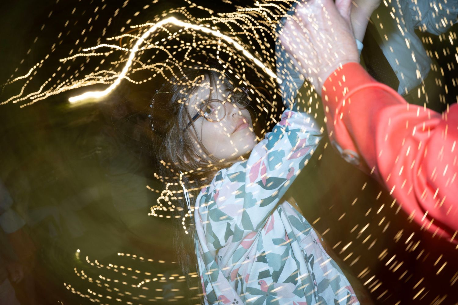 Dancer spinning under swirling light trails creating a dynamic nighttime party scene.