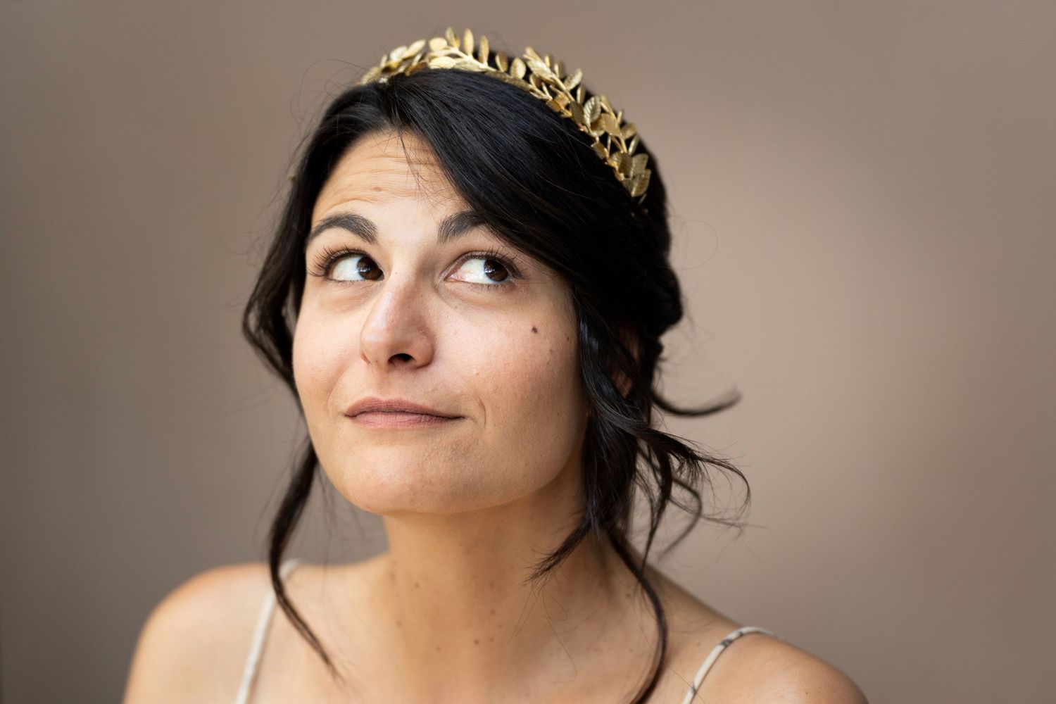 A person wearing a gold crown looks up with a reflective expression.