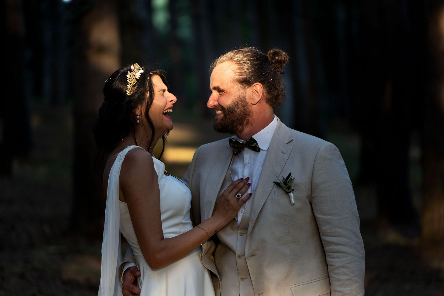 A romantic wedding portrait in a moody forest setting with soft lighting.